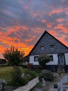 a house with a sunset in the background at Ferienwohnung Santino in Goslar