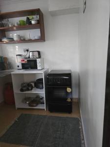 una piccola cucina con piano cottura e forno a microonde di Masons Tiny Cottage a Nairobi