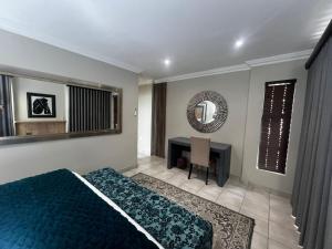 a bedroom with a bed and a desk and a mirror at Sasavona Luxury Cottage - 631 Euphoria Golf & Lifestyle Estate in Naboomspruit