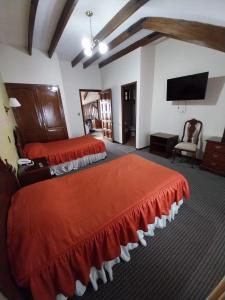 a bedroom with two beds and a flat screen tv at Paola Hostal in Sucre