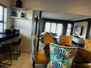 a dining room with a table and chairs and a living room at Sasavona Luxury Cottage - 631 Euphoria Golf & Lifestyle Estate in Naboomspruit
