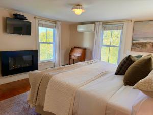 1 dormitorio con 1 cama grande y chimenea en Hideaway Inn Maine, en Camden