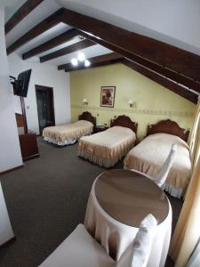 a hotel room with three beds and a table at Paola Hostal in Sucre