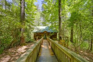 a bridge leading to a cabin in the woods at Near Lake Lure Quiet Cabin with Deck and Trail Access in Marion