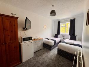 ein Hotelzimmer mit 2 Betten und einem TV in der Unterkunft High Trees Guest House Gatwick in Hookwood