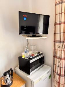 ein Wohnzimmer mit einem TV und einer Mikrowelle in der Unterkunft High Trees Guest House Gatwick in Hookwood