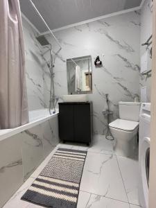 uma casa de banho branca com um lavatório e um WC em Апартаменты Freedom Greenline Сыганак Хан Шатыр em Taldykolʼ