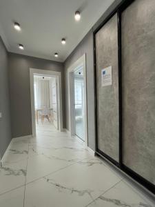 um corredor vazio com pisos em mármore e portas de vidro em Апартаменты Freedom Greenline Сыганак Хан Шатыр em Taldykolʼ