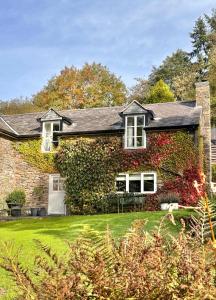 een stenen huis met een groene tuin bij River Cottage, a luxurious and cosy riverside cottage for two in Welshpool