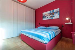 ein rotes Schlafzimmer mit einem Bett mit blauer und weißer Bettwäsche in der Unterkunft Giuseppe's House in Monserrato