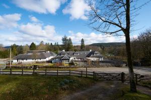 uma casa grande com uma cerca em frente em Home Farm Cottages, Glendaruel, Argyll. Scotland em Clachan of Glendaruel