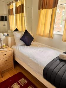 Schlafzimmer mit einem Bett und einem Fenster mit gelben Vorhängen in der Unterkunft High Trees Guest House Gatwick in Hookwood
