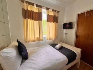 Schlafzimmer mit einem großen Bett und einem Fenster in der Unterkunft High Trees Guest House Gatwick in Hookwood