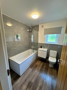 Un baño con bañera, inodoro y lavabo. en Inchmoan Apartment, en Bonhill