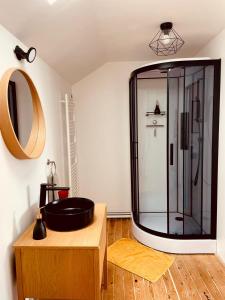 uma casa de banho com um lavatório preto e um espelho em Le Bercail em Plouézec