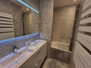 ein Badezimmer mit einem Waschbecken, einer Badewanne und einem Spiegel in der Unterkunft Appartement moderne et lumineux in Charenton-le-Pont