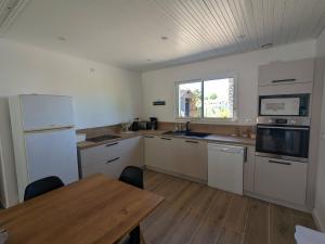 eine Küche mit weißen Geräten und einem Holztisch in der Unterkunft Maison 3 chambres Longeville in Longeville-sur-Mer + 3 Fotos