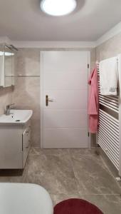 La salle de bains est pourvue d'une porte blanche et d'un lavabo. dans l'établissement Hisa idej, à Sežana