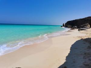 a beach with the blue water and rocks at Caves Camp Matrouh in Kafr Abu Habhab
