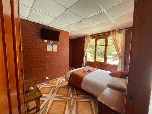 a bedroom with a bed and a window and a tv at Playita Salomon in Baños