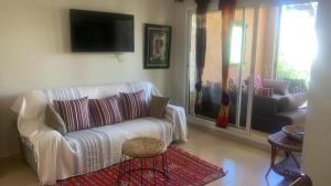 uma sala de estar com um sofá e uma televisão em résidence golfique em Fez