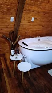 a bathroom with a bath tub and a glass of wine at Chalé romântico São Bento do Sapucaí - Jacuzzi - Chalé Gênova in São Bento do Sapucaí +35 photos