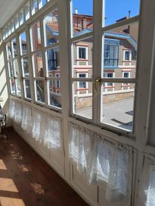 a window with white curtains and a view of a street at El espolon in Comillas