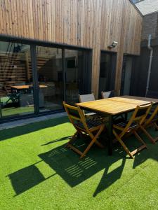 une table et des chaises en bois assises sur une pelouse dans l'établissement L’Usine, à Concarneau