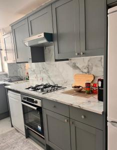 a kitchen with gray cabinets and a stove top oven at Hyde Park,3 min walk,Family home! 2 Bedrooms & 2 Bathrooms Apartment! Fantastic Location in London