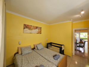 um quarto com uma cama e uma parede amarela em Away but Home em San Miguel de Abona
