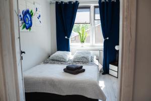 niewielka sypialnia z łóżkiem z niebieskimi zasłonami w obiekcie Welcome w Ostródzie