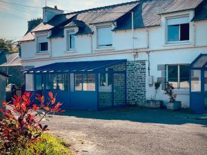 une maison blanche avec un garage bleu devant elle dans l'établissement Le Bercail, à Plouézec