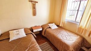 two beds in a small room with a window at Cabañas Pinamar in La Serena