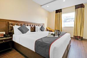 Grand Empire Suites By Delhi Airport في نيودلهي: غرفه فندقيه بسرير ونافذه