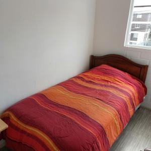 Una cama con una manta de colores en una habitación en Maria y Carlos Departamento 5 personas independiente cerca de Viña del Mar, en Villa Alemana