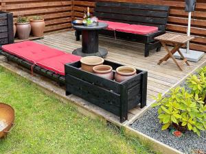 a wooden deck with a bench and a table with pots at 4 person holiday home in Gilleleje in Gilleleje