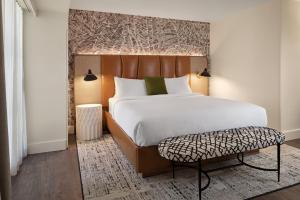 a bedroom with a large bed and a bench at Burton House, Beverly Hills, A Tribute Portfolio Hotel in Los Angeles