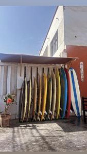 Un montón de tablas de surf están alineadas contra un edificio. en Pointbreak Surf Camp, en Huanchaco