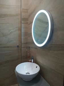 a bathroom with a white sink and a round mirror at enjoy your holidays with us in Attard