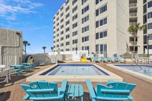 Una piscina con sillas azules y un edificio. en 721 Top Of The Gulf, en Panama City Beach
