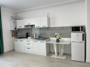 cocina blanca con mesa y nevera en Apartament R en Giroc