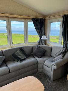 a living room with a couch and three windows at Gwêl y Gorwel- Horizon View in Llangwnadl