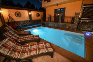 a swimming pool with two chairs next to a house at Nevan Luna Home in Câmpia Turzii