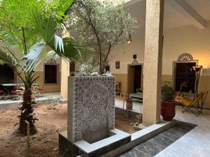 a courtyard with a fountain in a building with trees at Riad Dar Tazoulte in Agdz