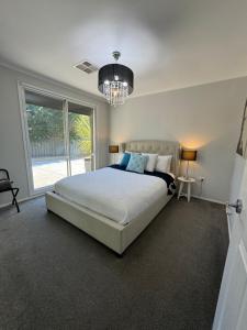 a bedroom with a large bed and a chandelier at Belle in Bowral in Bowral
