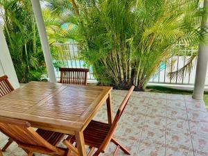 einen Holztisch und Stühle auf einer Terrasse mit Palmen in der Unterkunft Bleu Soleil in Le Morne-Vert