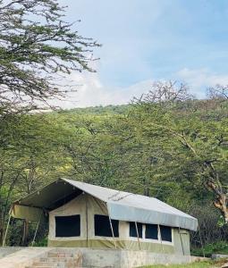 a building with a tin roof in a field at Wildlife Enthusiasts in Sekenani