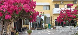 un patio con mesas, sillas y flores rosas en Esperides Hotel, en Myrtos