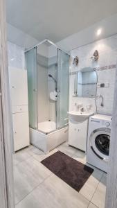 a bathroom with a shower and a washing machine at Welcome in Ostróda