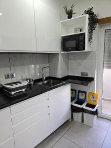 cocina blanca con fregadero y microondas en LC's Guesthouse, en Lagos
